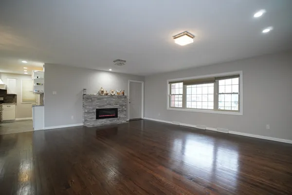an empty room with wooden floor fireplace and windows