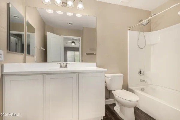 a bathroom with a toilet a sink a mirror a shower a vanity and window