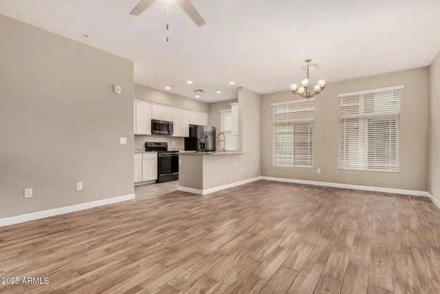 an empty room with wooden floor and kitchen view
