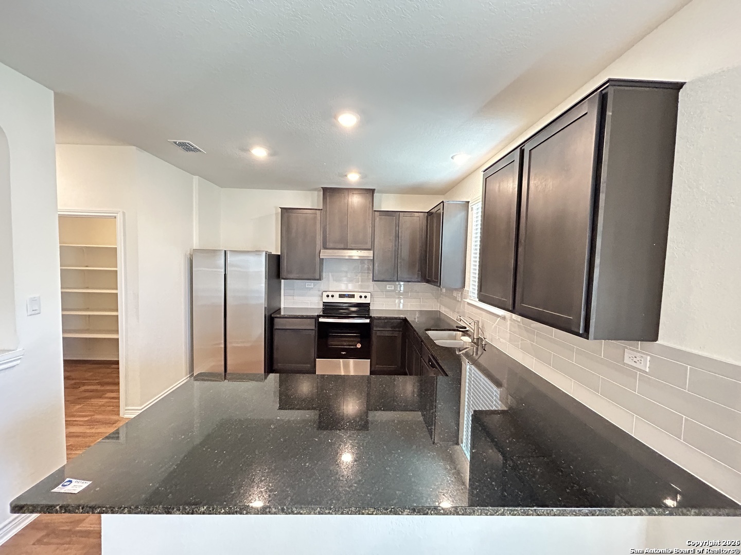 6608 Runaway Row Converse, TX 78109 - Photo 4 of 17 a kitchen with stainless steel appliances kitchen island granite countertop a refrigerator and a sink