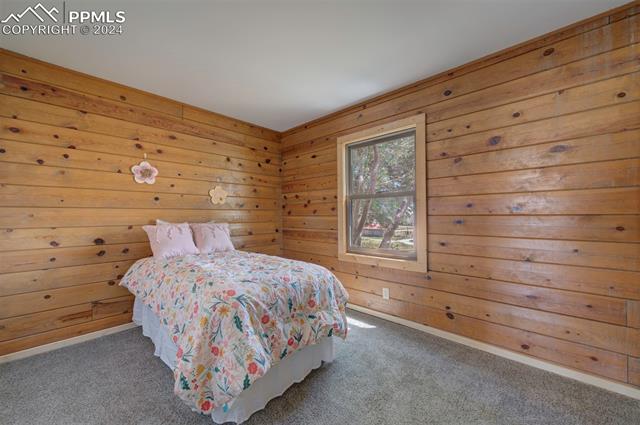 19350 Lemesany Road Calhan, CO 80808 - Photo 24 of 46 Bedroom with carpet and wooden walls