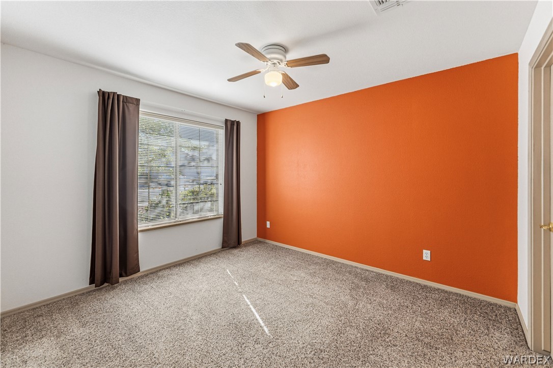3973 Prairie View Drive Kingman, AZ 86409 - Photo 24 of 34 Room featuring a window with brown curtains, carpeted flooring, and a ceiling fan