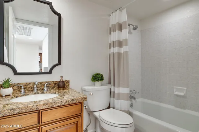 a bathroom with a granite countertop sink mirror vanity and toilet