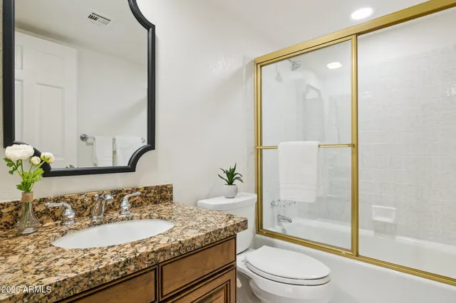 a bathroom with a granite countertop sink toilet and shower