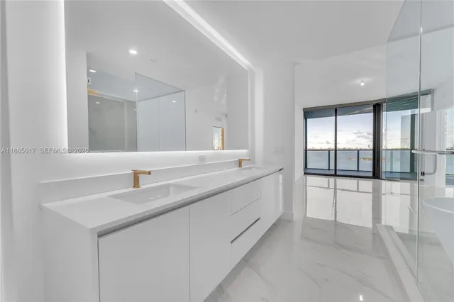 a large white kitchen with a sink and dishwasher with a large window
