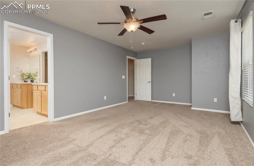 4815 Harrier Ridge Drive Colorado Springs, CO 80916 - Photo 24 of 33 Unfurnished bedroom with light colored carpet, ceiling fan, and ensuite bathroom
