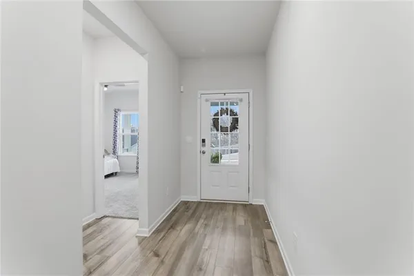 a view of a hallway with wooden floor and a bathroom