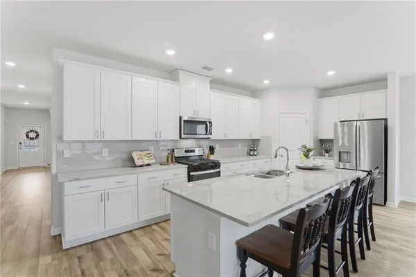 a kitchen with a sink a stove a refrigerator and white cabinets with wooden floor