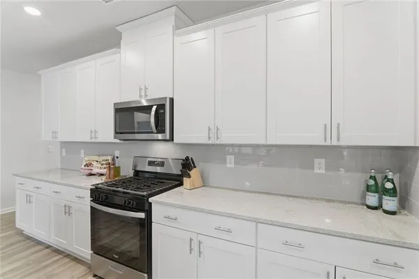 a kitchen with stainless steel appliances granite countertop white cabinets a sink and dishwasher