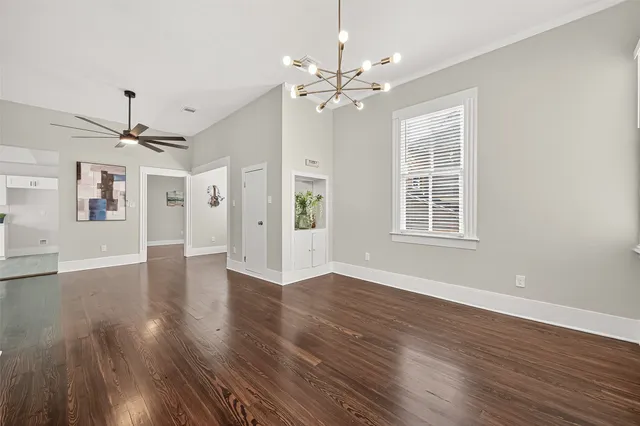 a view of an empty room with wooden floor and a window