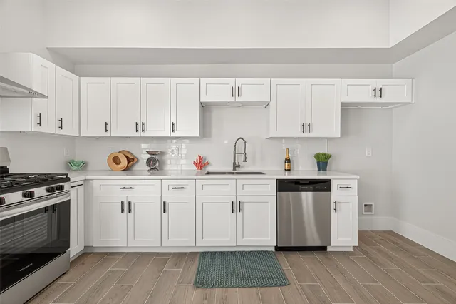 a kitchen with cabinets appliances and wooden floor