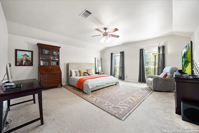 a spacious bedroom with a bed a dresser and a chandelier
