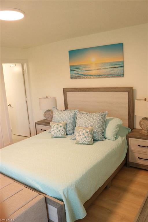 2235 San Marco Road, Unit 5204 Marco Island, FL 34145 - Photo 3 of 34 Spacious bedroom featuring wood-finish flooring, a light wood-tone headboard, and dual nightstands with drawer storage