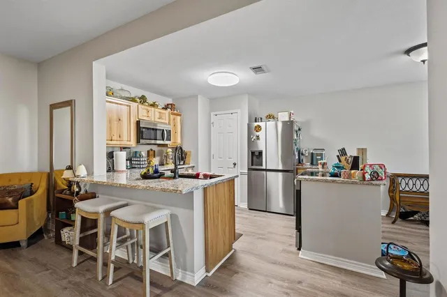 a kitchen with stainless steel appliances granite countertop a stove top oven a sink dishwasher and a refrigerator with wooden floor