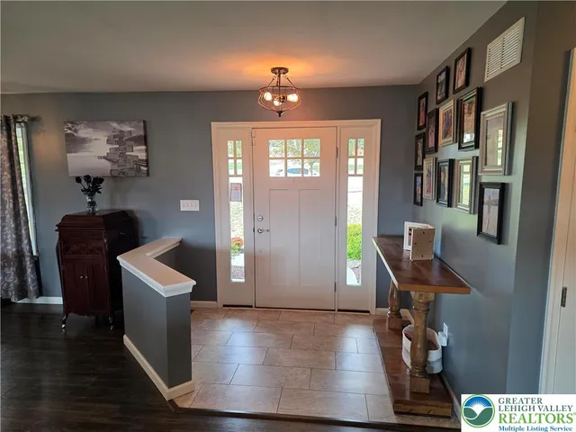 a dining room with wooden floor a chandelier a wooden table and chairs