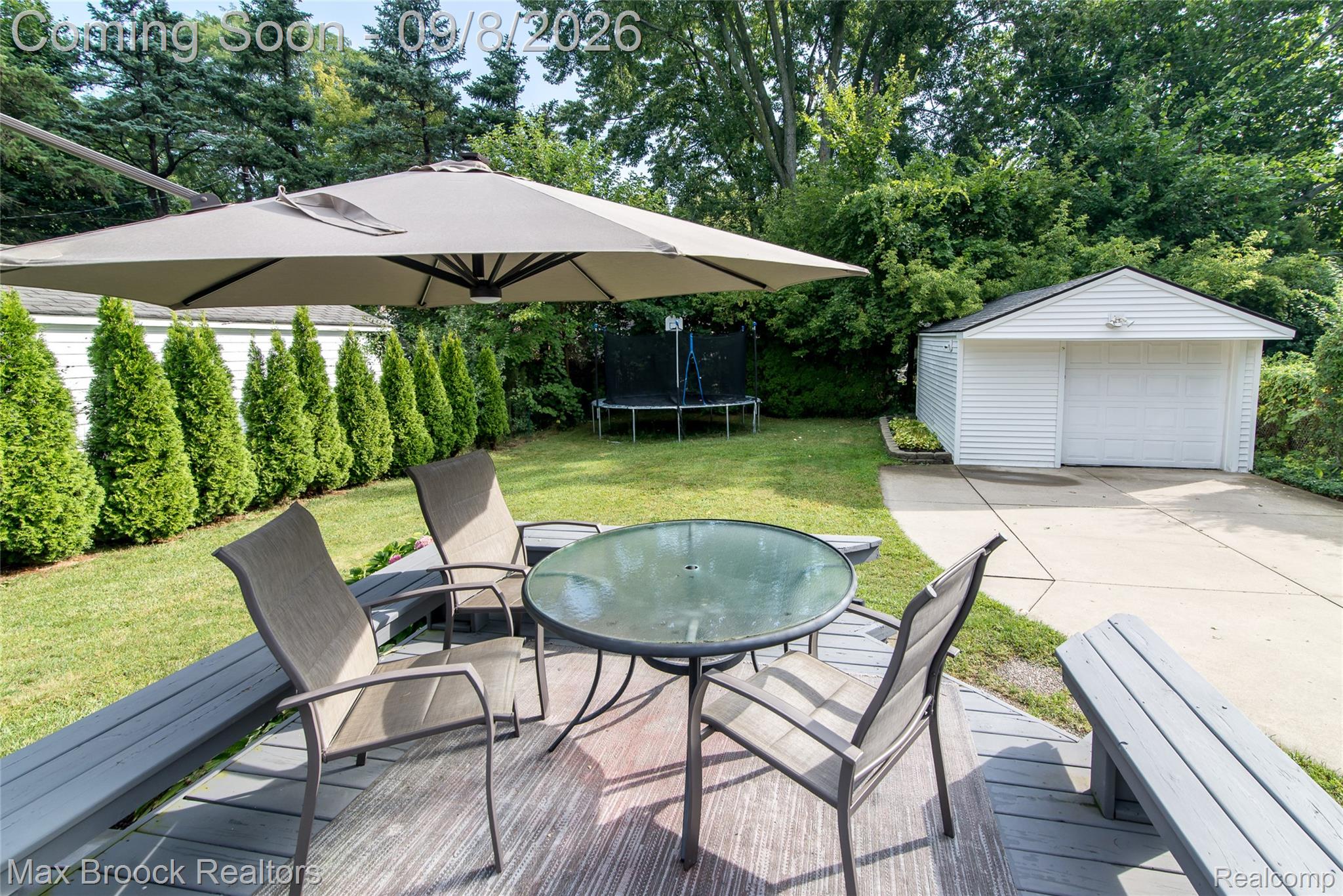 1533 Mansfield Road Birmingham, MI 48009 - Photo 39 of 48 Spacious backyard featuring a wood-finish deck, manicured lawn, mature trees, and a detached two-car garage with a concrete driveway