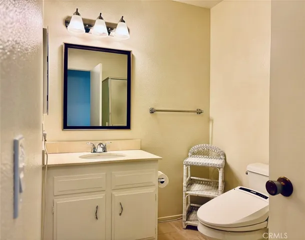 a bathroom with a toilet sink vanity and mirror