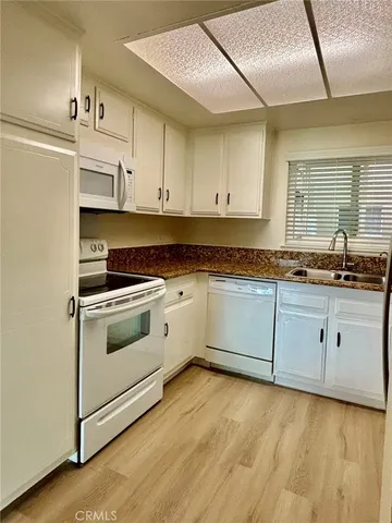 a kitchen with granite countertop white cabinets and white appliances