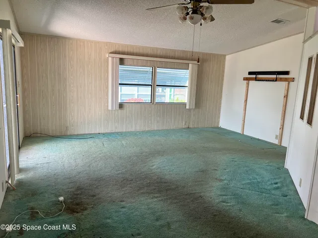 an empty room with a ceiling fan and a window