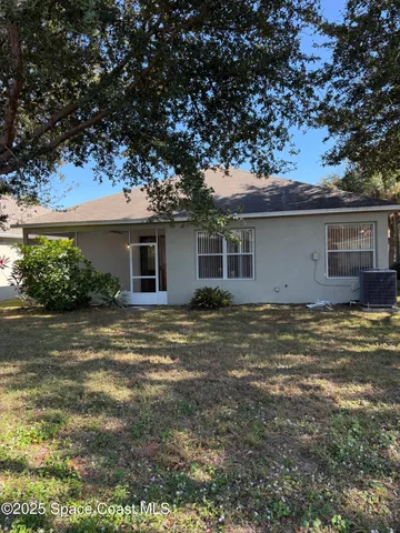 a backyard of a house with plants and large tree