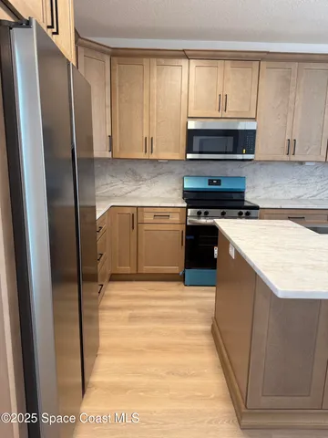 a kitchen with stainless steel appliances granite countertop a refrigerator a stove and a sink