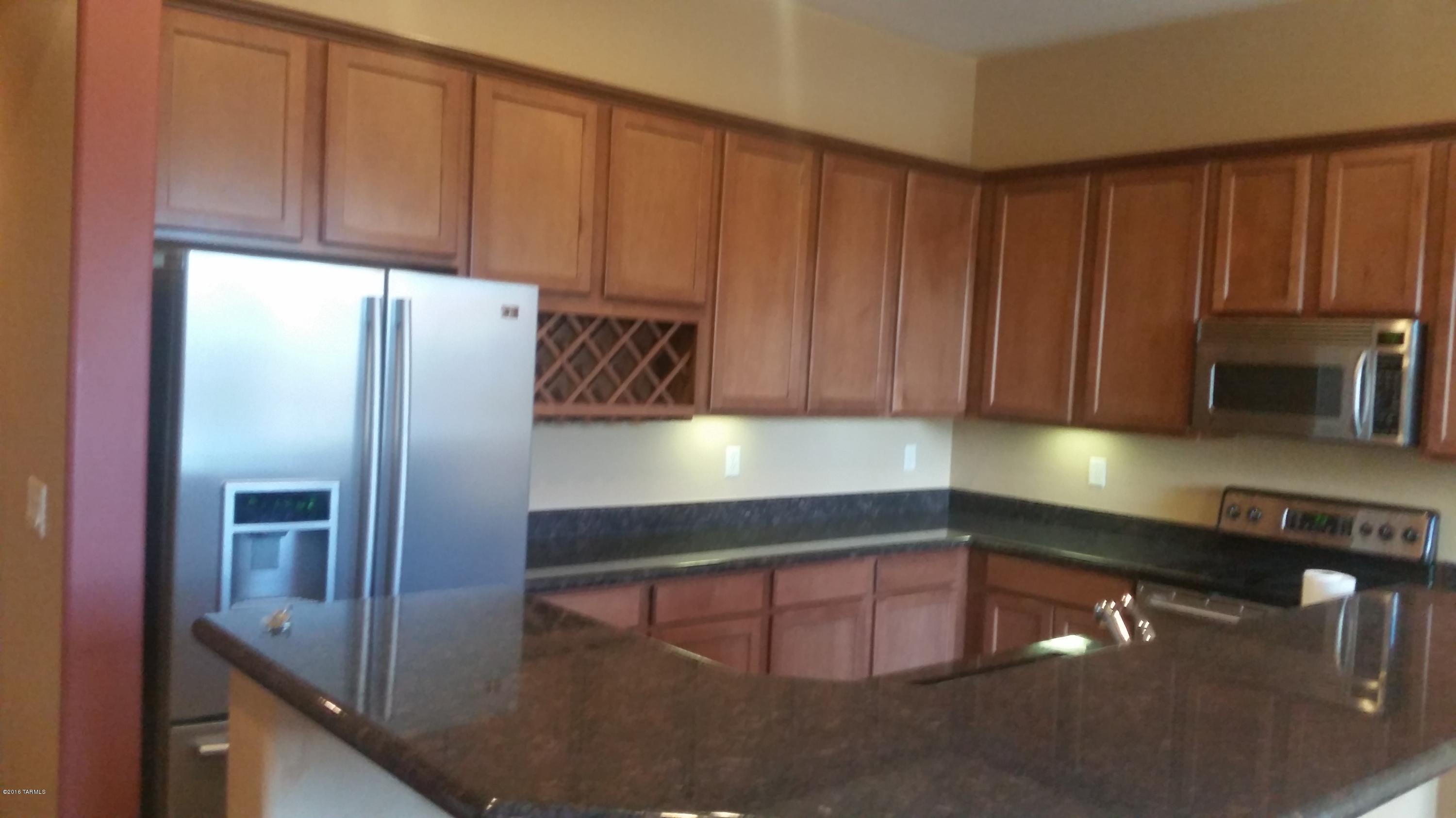 478 East Cedarvale Road Tucson, AZ 85704 - Photo 5 of 39 a kitchen with stainless steel appliances granite countertop a refrigerator a stove and a sink with wooden cabinets