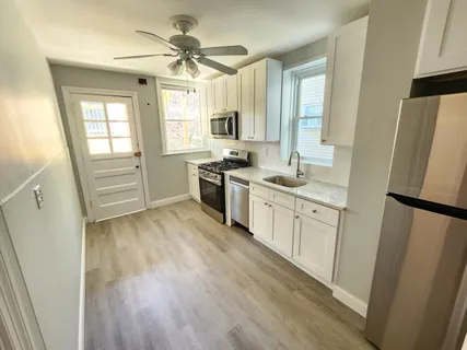 a kitchen with stainless steel appliances white cabinets a stove top oven a sink and dishwasher