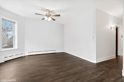 an empty room with wooden floor chandelier fan and windows