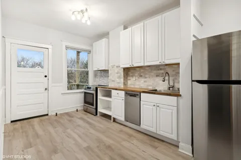 a kitchen with a refrigerator and white cabinets