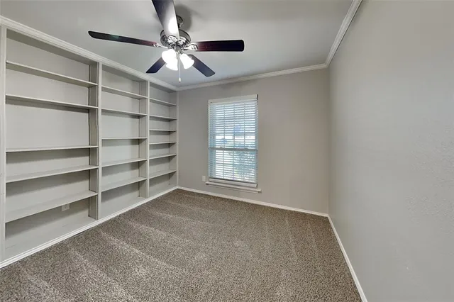 a view of an empty room with a window and a ceiling fan