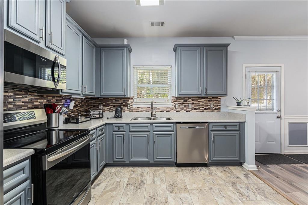 1111 Watercourse Way Hampton, GA 30228 - Photo 11 of 30 a kitchen with stainless steel appliances granite countertop a sink stove a microwave and cabinets