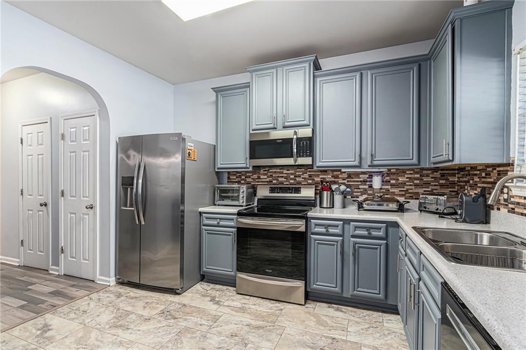 1111 Watercourse Way Hampton, GA 30228 - Photo 12 of 30 a kitchen with stainless steel appliances granite countertop a sink stove and refrigerator