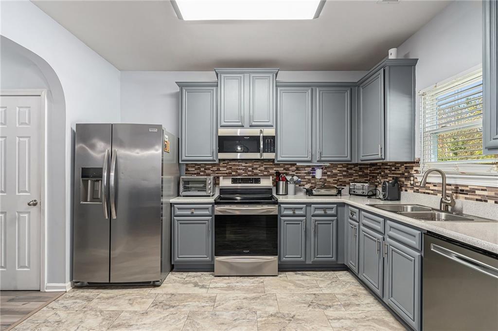 1111 Watercourse Way Hampton, GA 30228 - Photo 13 of 30 a kitchen with stainless steel appliances granite countertop a sink stove and refrigerator