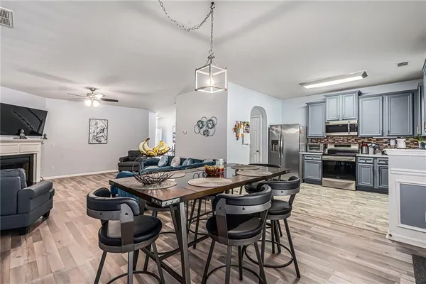 a kitchen with stainless steel appliances kitchen island granite countertop a stove a sink dishwasher a dining table and chairs with wooden floor