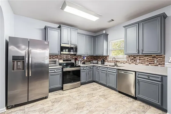 a kitchen with stainless steel appliances granite countertop a stove top oven a refrigerator and a sink