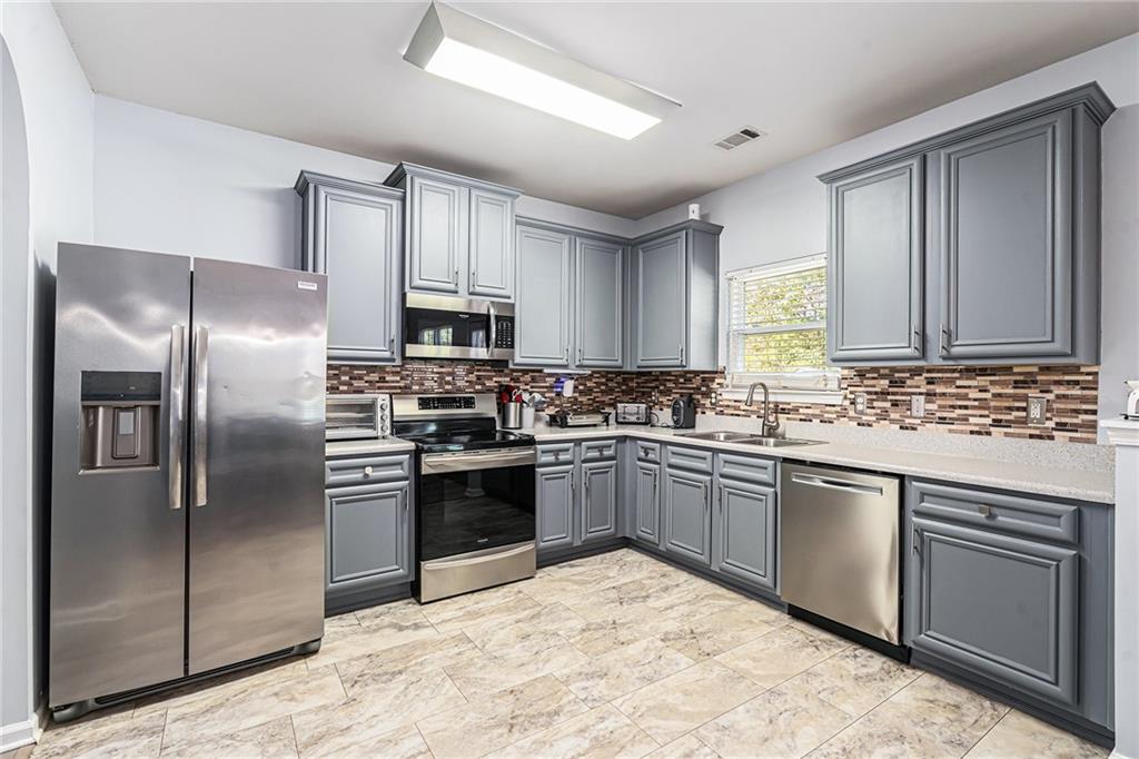 1111 Watercourse Way Hampton, GA 30228 - Photo 10 of 30 a kitchen with stainless steel appliances granite countertop a stove top oven a refrigerator and a sink