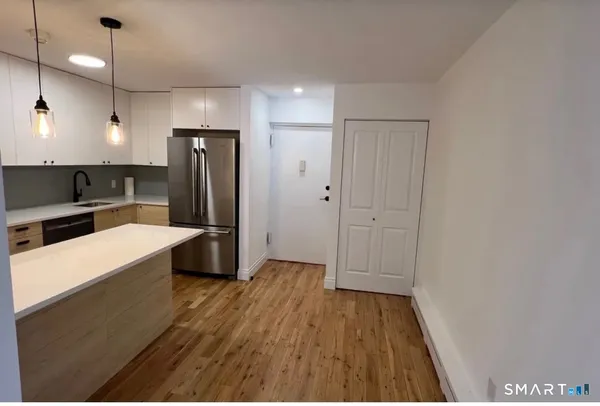 a kitchen with stainless steel appliances a refrigerator and a wooden floor