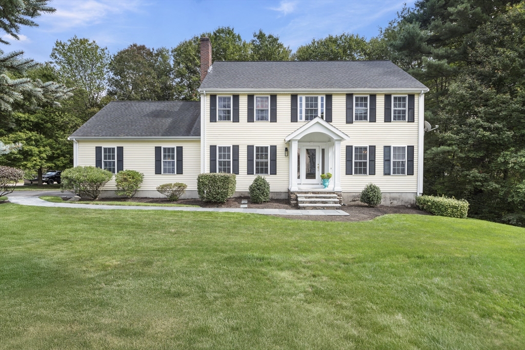 a front view of a house with a garden and trees