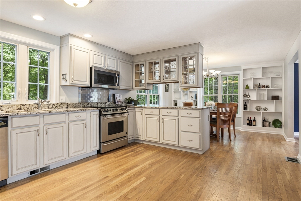 2 Gerald Avenue Millis, MA 02054 - Photo 11 of 38 a kitchen with stainless steel appliances white cabinets a sink a stove a dining table and chairs