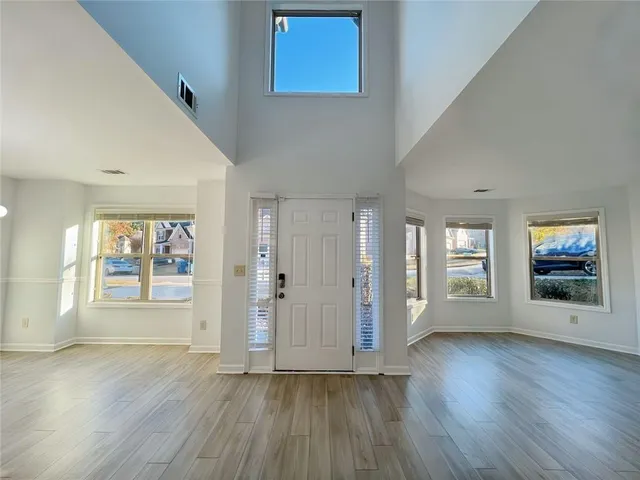 a view of an empty room with wooden floor and a ceiling fan