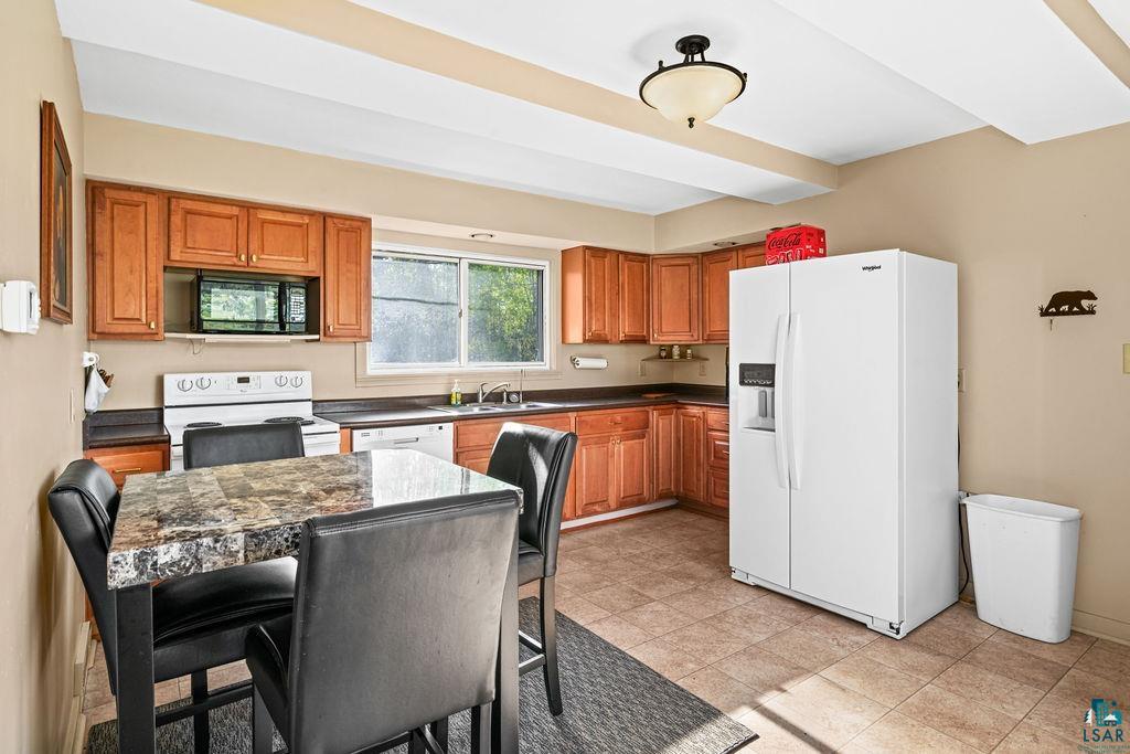 4543 County Road East South Range, WI 54874 - Photo 11 of 43 Kitchen featuring wood cabinetry, white appliances, a window above the sink, recessed lighting, and tile flooring