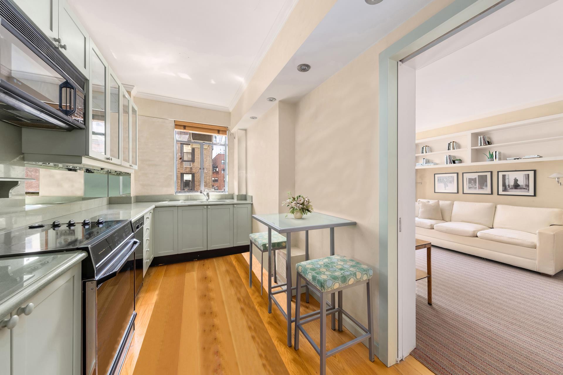 19 East 88th Street, Unit 9C Manhattan, NY 10128 - Photo 4 of 9 a kitchen with stainless steel appliances granite countertop a stove top oven a sink dishwasher and cabinets with wooden floor