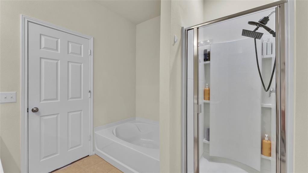 707 Indigo Road Princeton, TX 75407 - Photo 19 of 29 Bathroom featuring a soaking tub, a multi-function shower with a glass enclosure, built-in shower shelving, and a six-panel interior door