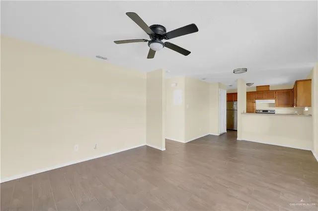 a view of empty room with wooden floor and ceiling fan