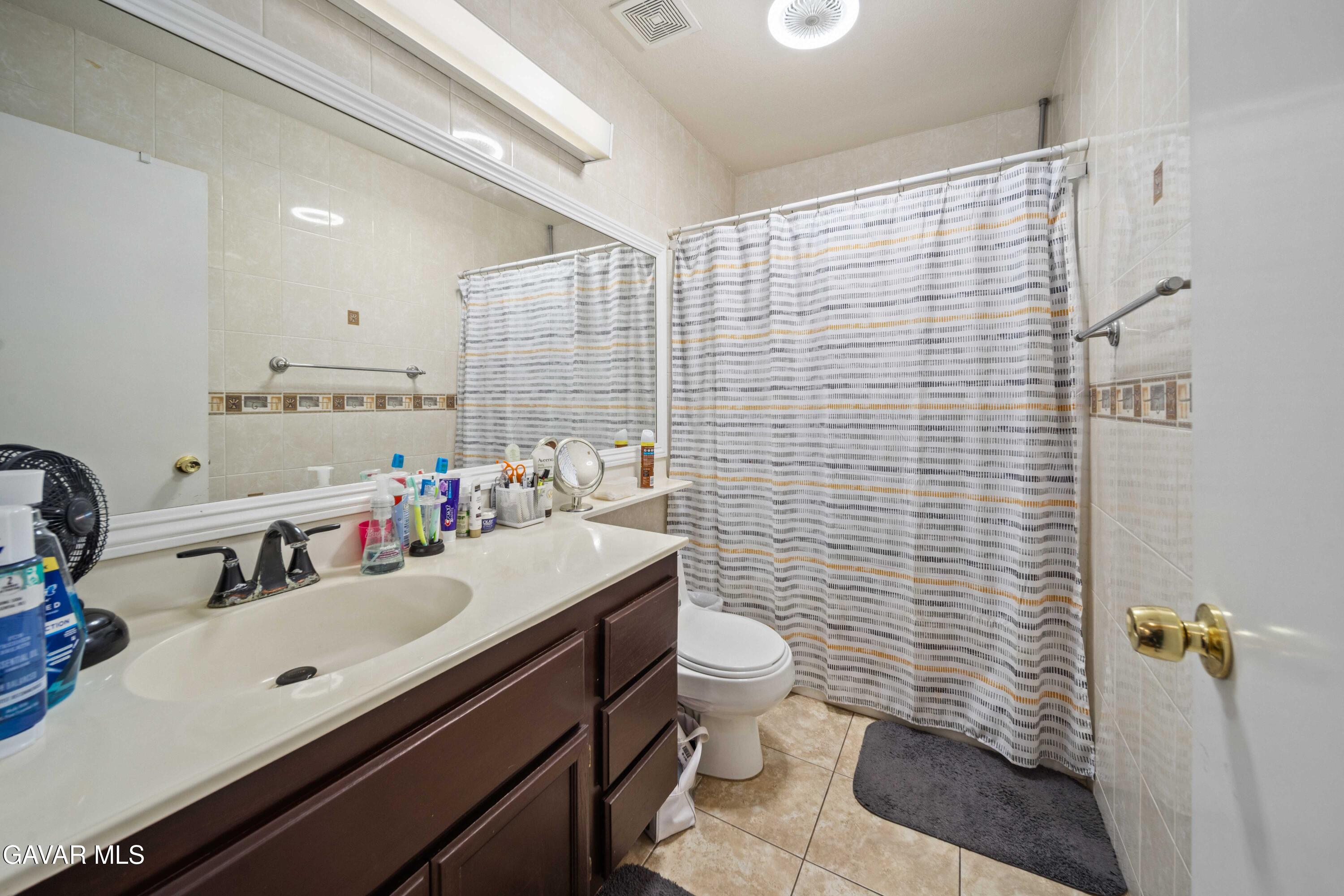 45736 Victoria Avenue Lancaster, CA 93534 - Photo 21 of 30 a bathroom with a sink a toilet and shower curtain
