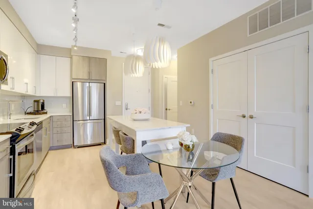 a kitchen with stainless steel appliances a refrigerator a sink a stove a dining table and chairs