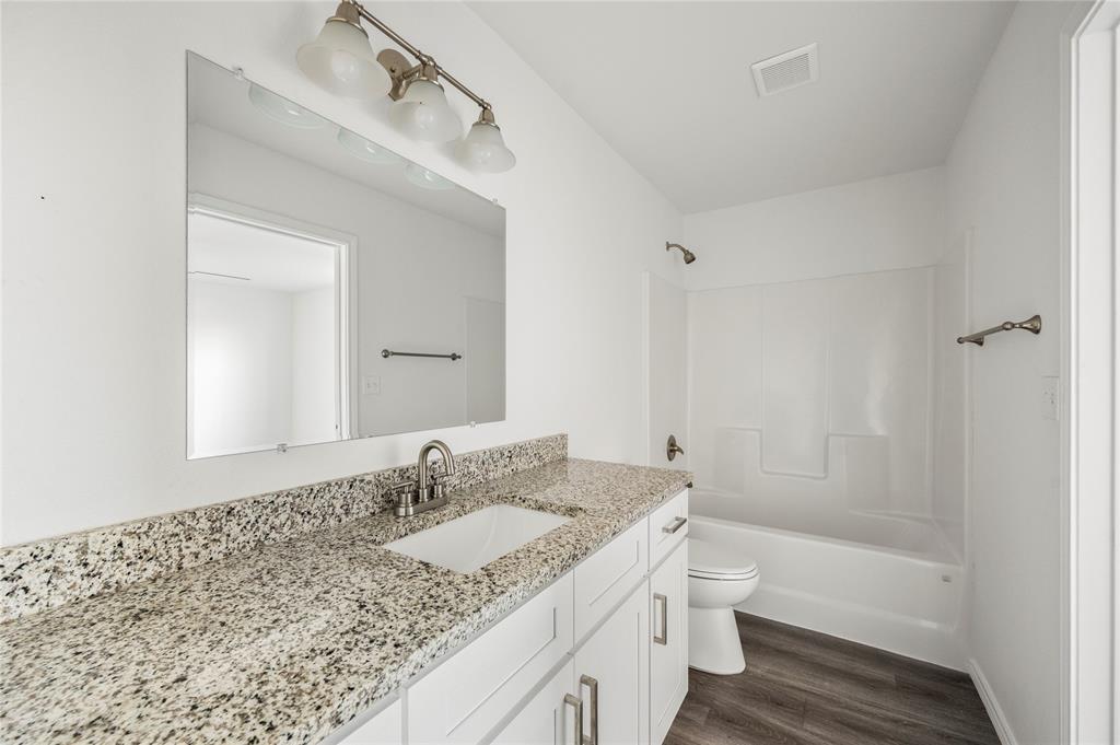 437 Whitney Court Rio Vista, TX 76093 - Photo 19 of 21 a bathroom with a granite countertop sink toilet and shower