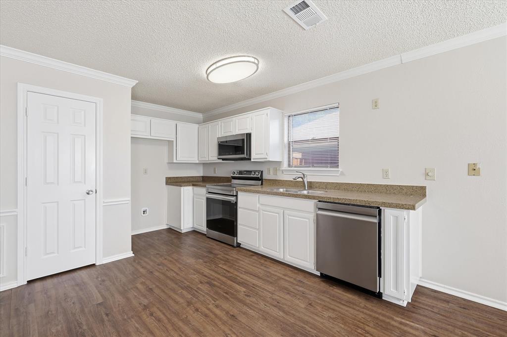 318 Lodge Road Coppell, TX 75019 - Photo 19 of 35 A spacious kitchen with white cabinetry, stainless appliances and generous open space for dining, entertaining and daily routines.