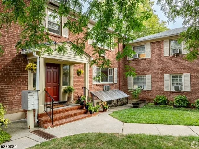 a view of a brick house with a yard and large tree