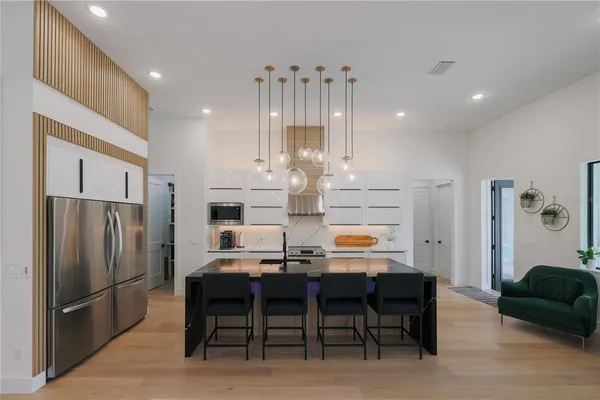 a kitchen with stainless steel appliances a dining table chairs and refrigerator